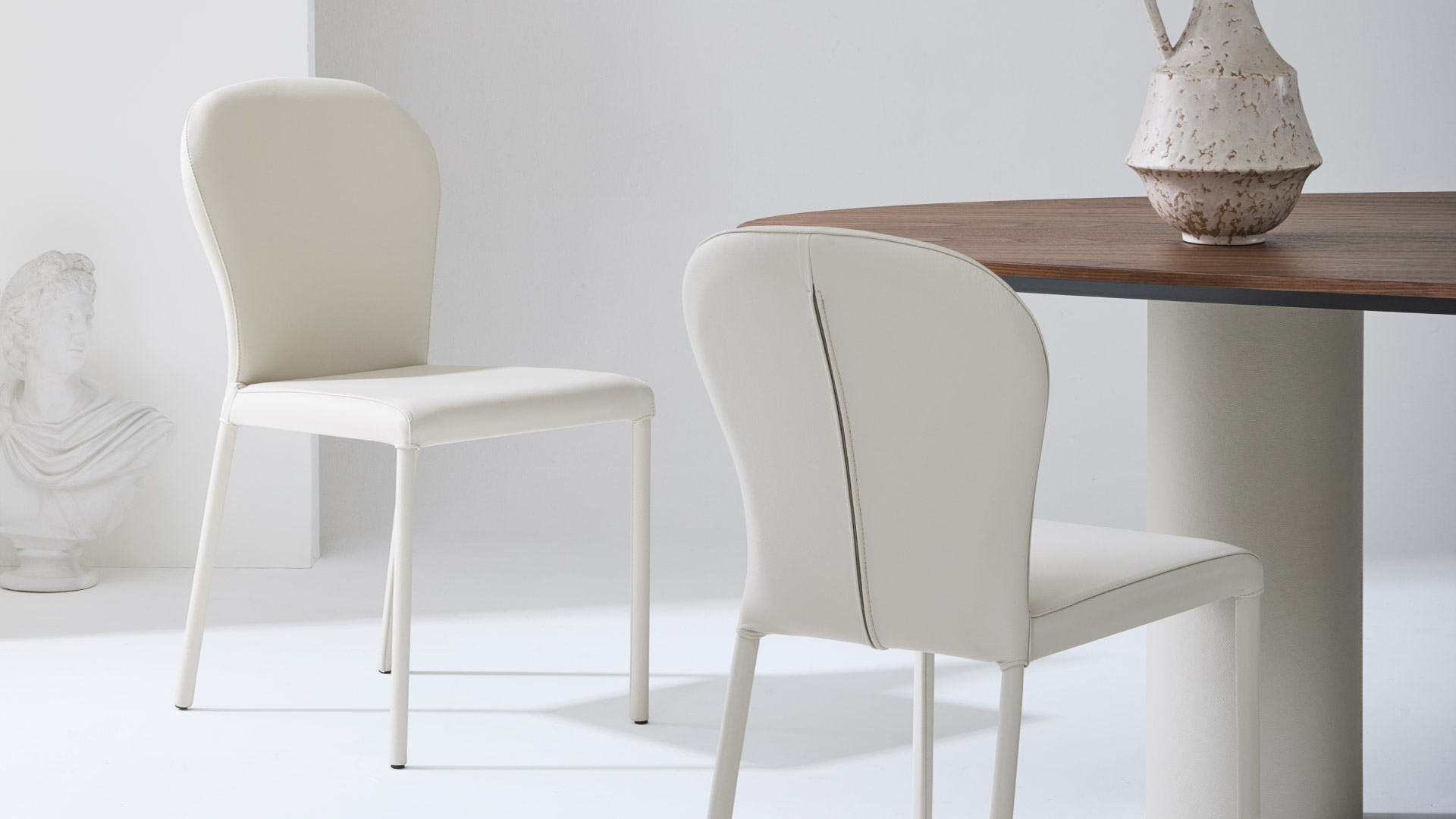 Sedie in pelle di design Gaia Julia Italia attorno a tavolo, soluzione per ambienti dining residenziali e contract