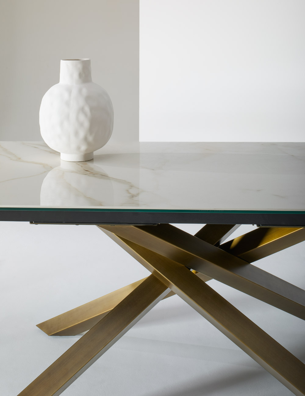 Dettaglio della base scultorea del tavolo di design Mikado Julia Italia con piano in ceramica effetto marmo e vetro