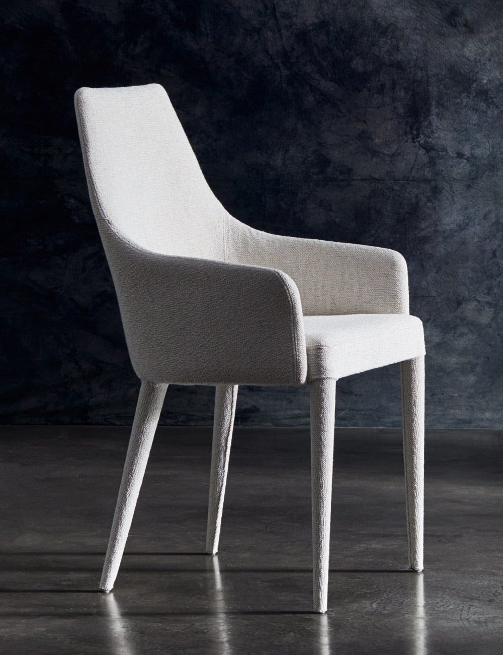 Sedia di design Evelin Julia Italia rivestita in tessuto, scatto lifestyle in studio con fondo scuro